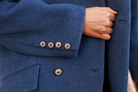 Closeup of woman hand holding handbag in autumn park. Woman in blue coat. fashion look detailsの写真素材