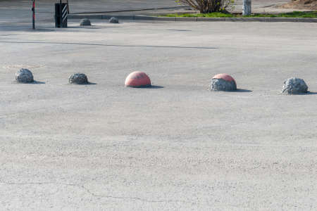 Old worn concrete parking hemispheres on asphalt