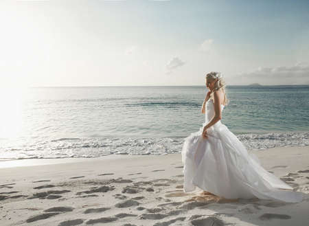 Beautiful lovely bride walking on the beach on sunset. Great, colorful wedding on sunset in tropical country.の写真素材