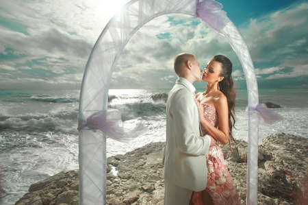Young, sexy and attractive couple standing under arch during wedding ceremony in tropical island. Dream wedding in exotic country, caribbean or Hawaii.の写真素材