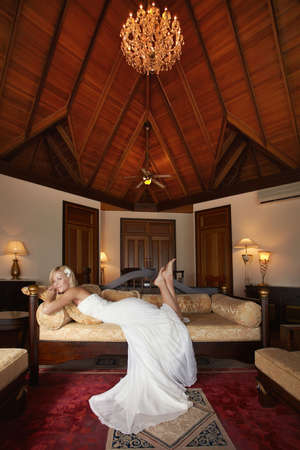 Gorgeous, lovely bride, model lying on sofa in beautiful villa.  Cozy atmosphere and spacious room.の写真素材