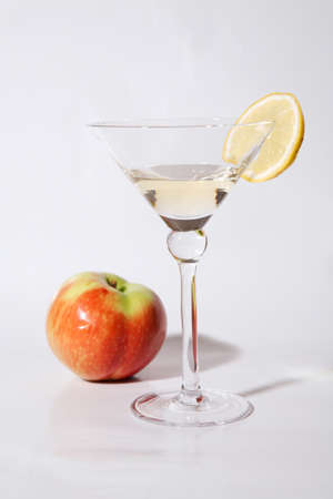 A glass of white wine with red apple and lemonの写真素材