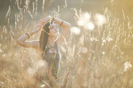 Girl in the grass in the setting sunの写真素材