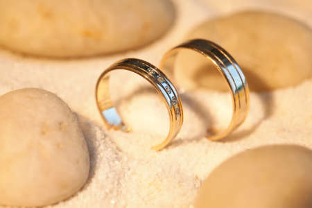 Wedding rings in the sand with stonesの写真素材