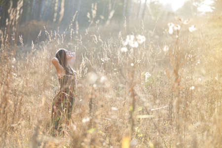 Girl in the grass in the setting sunの写真素材