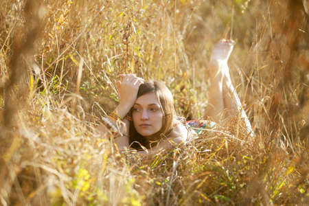 Girl in the grass in the setting sunの写真素材