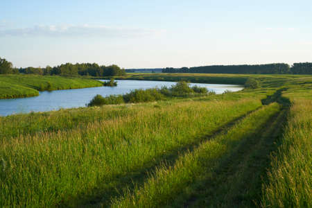 Green meadow with lake and hillsの写真素材