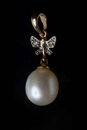 Gold pendant with a pearl on a black background.の写真素材