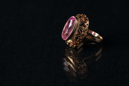 Golden ring with a ruby on a black background.の写真素材