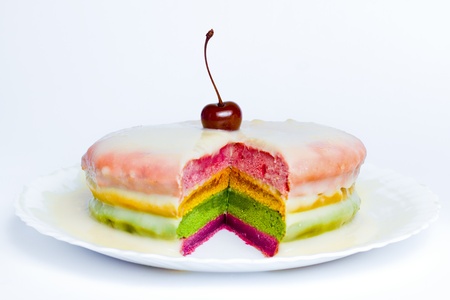 A colorful cake decorated with a cherry on the top; 