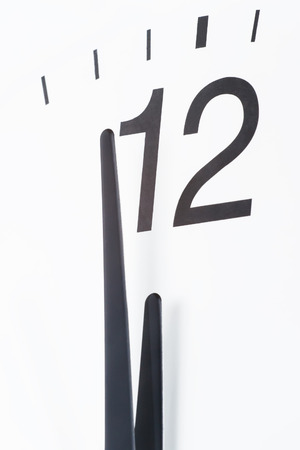 Close up of a clock face showing the hands at two minutes to midnight
