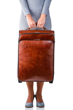 Woman in grey dress holds leather suitcase with copy spaceの写真素材