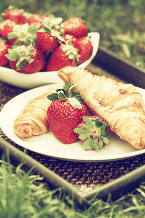 Breakfast outdoors with croissants and strawberries. Toned imageの写真素材