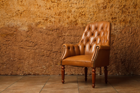 Leather armchair against stone wall. Vintage armchair in loft.の写真素材