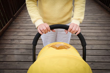 Young woman strolling a carriage outdoor. Closeup shot of female hands with stroller handleの写真素材