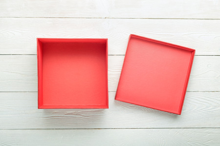 Blank red gift box with lid on white wooden background. Flat lay. View from aboveの写真素材