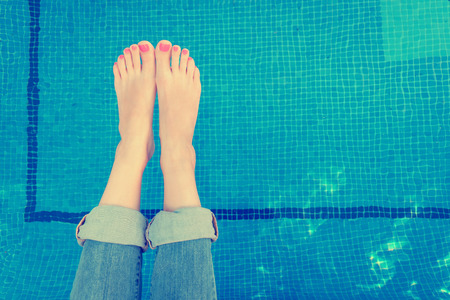 Above view on woman legs rolled up jeans while relaxing by the swimming poolの写真素材