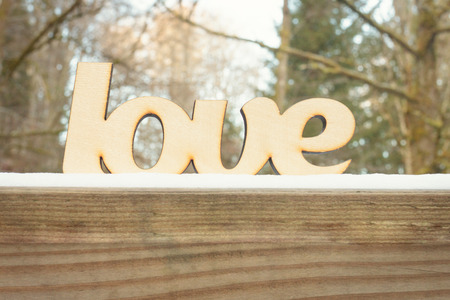 Abstract wooden love sign on wooden texture with snow in winter forest. Winter weather conceptの写真素材