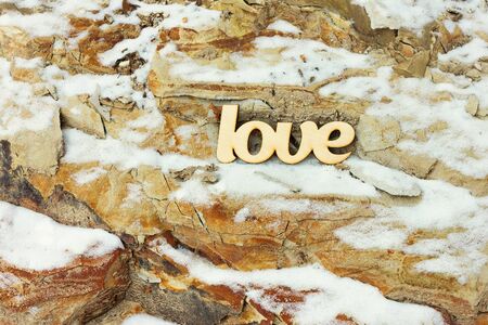 Wooden love sign on stone rock background with snow. Love conceptの写真素材