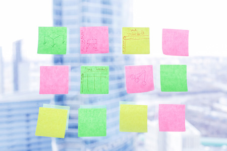 Colorful sticky notes on window in the office with skyscrapers on backgroundの写真素材