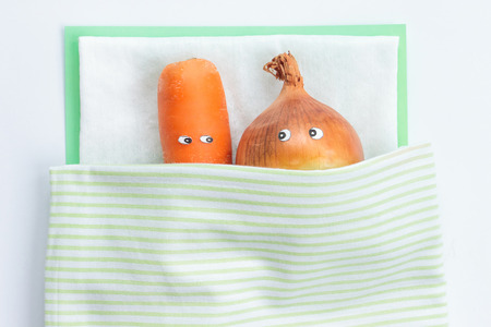Young couple carrot with leek lying together in bed. Top view. Funny food concept. Sex conceptの写真素材