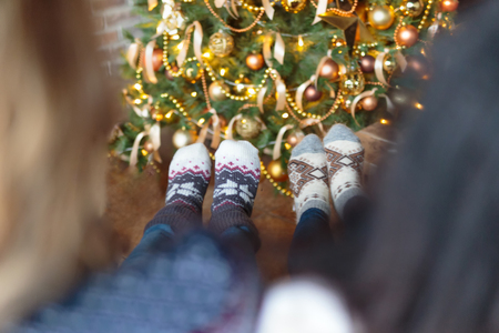 Two women dressed Christmas socks sitting near decorated Christmas tree. Rear viewの写真素材