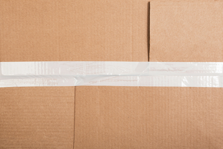Corrugated cardboard with a white sticky tape. Cardboard box background.の写真素材