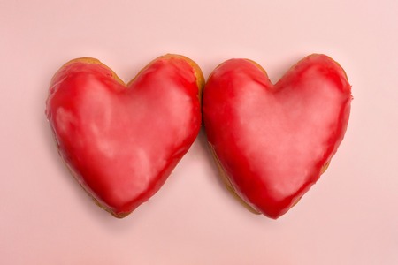 Valentine heart shaped red donuts on pink background. Flat lay. Top viewの写真素材
