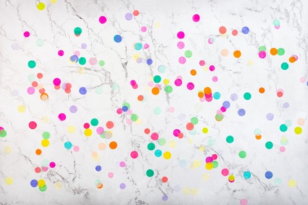 Colorful confetti on white marble background. Colorful confetti background. Flat lay