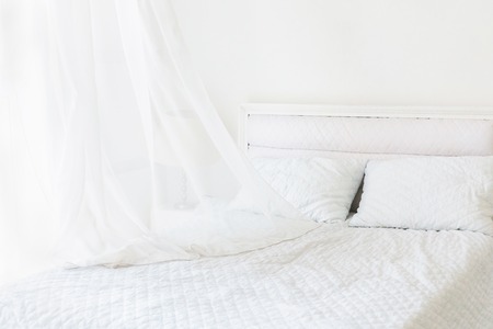 White room minimal interior design. White bed with pillows in white room