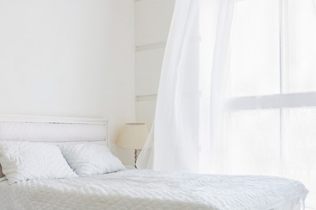 White bedroom minimal interior with white bed, big window with white curtainsの写真素材