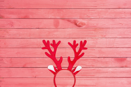 Flat lay of antlers of a deer headband on pink wooden background. Toy reindeer horns on pink textureの写真素材