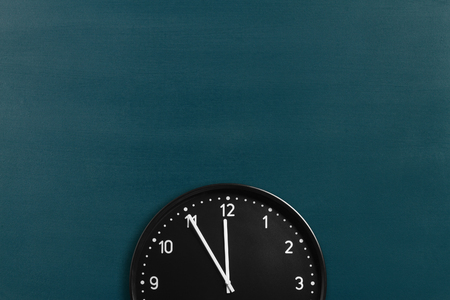 Round wall clock showing 5 minutes to midnight on chalkboard background. Crop image with space for promo copyの写真素材