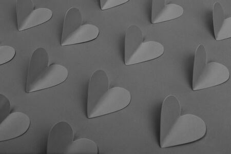 Black paper hearts on gray background. Closeup of gray paper hearts
