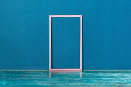 Blank pink frame on the floor against blue wall background