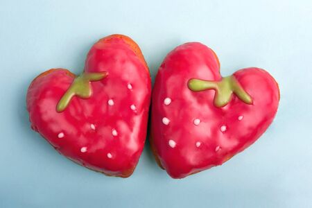 Sweet heart-shaped strawberry cakes on blue background. Sweet cakes for Valentines day. Flat lay....