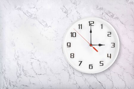 White round wall clock on white natural marble background. Three oclock, 3 a.m. or 3 p.m.の写真素材