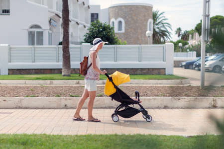 Young mother pushing stroller with sleeping baby by the streetの写真素材