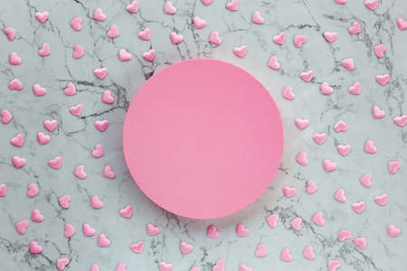 Pink round box on marble background with many tiny hearts. Round gift box on marble texture with satin hearts. Top view. Flat lay.の写真素材