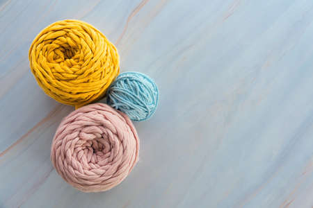 Top view of round colorful skeins of cotton yarns for macrame knitting with blank space.
