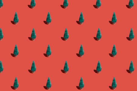 Christmas pattern background of green Christmas trees on red texture. Minimal New Year conceptの写真素材