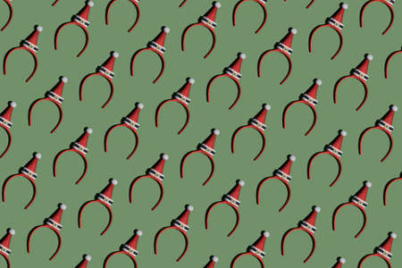 Christmas pattern of funny headbands with red Santa hats on green backgroundの写真素材