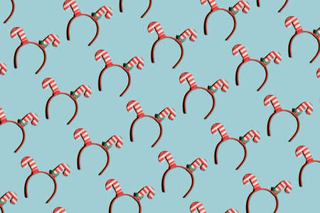 Christmas pattern of red striped headband horns as Christmas caramel canes on light blue background.