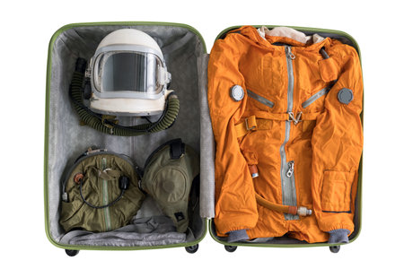 Open suitcase packed for space travelling with astronaut orange space suit, space helmet and spacesuit accessories isolated on white backgroundの写真素材