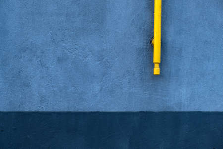 Abstract wall background with blue concrete texture and yellow pipeの写真素材