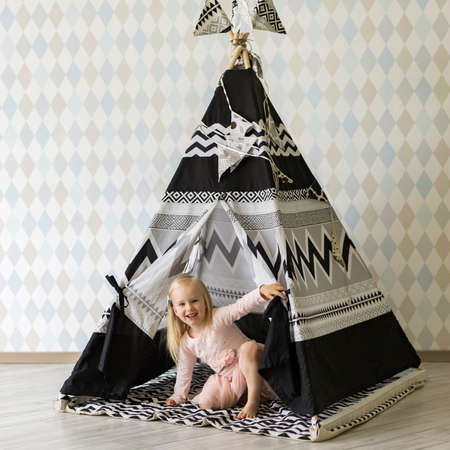 Happy blonde 3-4 years old girl playing in children play tent indoorsの写真素材