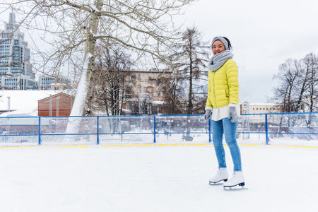 African american woman having figure ice skating on ice rink. Attractive African woman doing figure skatingの写真素材