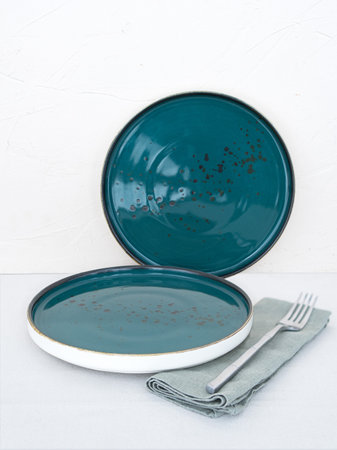 Two empty blue dinner plates with tablecloth on table with white backgroundの写真素材