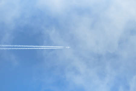airplane flying across the blue sky with clouds