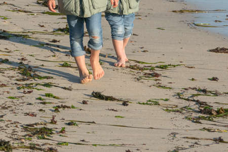 two kids walking barefoot on sand doing earthingの写真素材